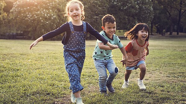 Three children playing outside on the grass.